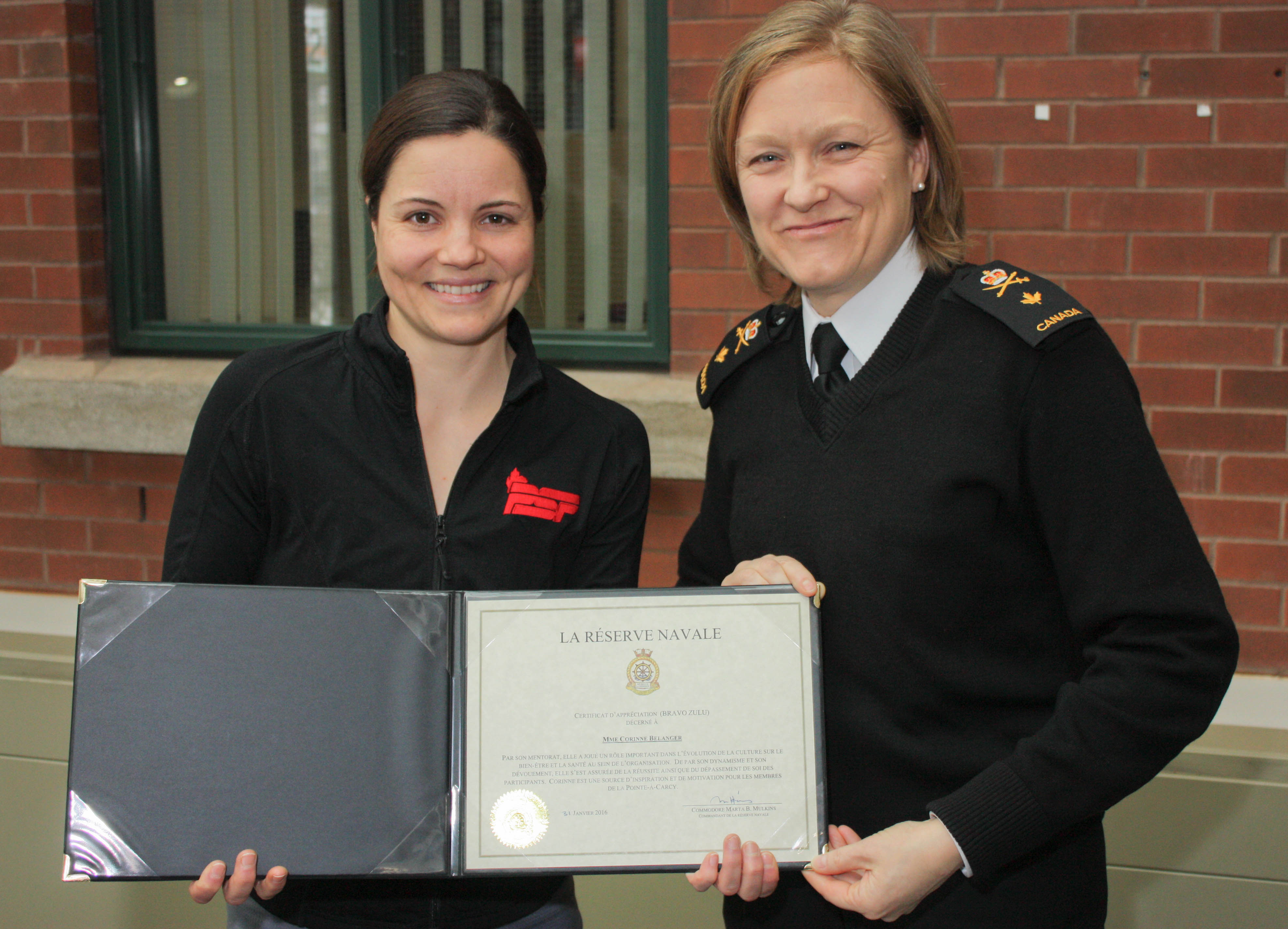 Mme Corinne Bélanger reçoit le « Bravo Zulu » du commandant de la Réserve navale des mains du commodore Marta B. Mulkins, commandant de la Réserve navale, au Quartier général de la Réserve navale à Québec, le 2 février 2016. 