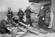 Des marins du destroyer Algonquin (classe V) nettoient leur canon de 4,7 pouces (12 cm) après un bombardement des défenses côtières allemandes depuis la tête de pont en Normandie.