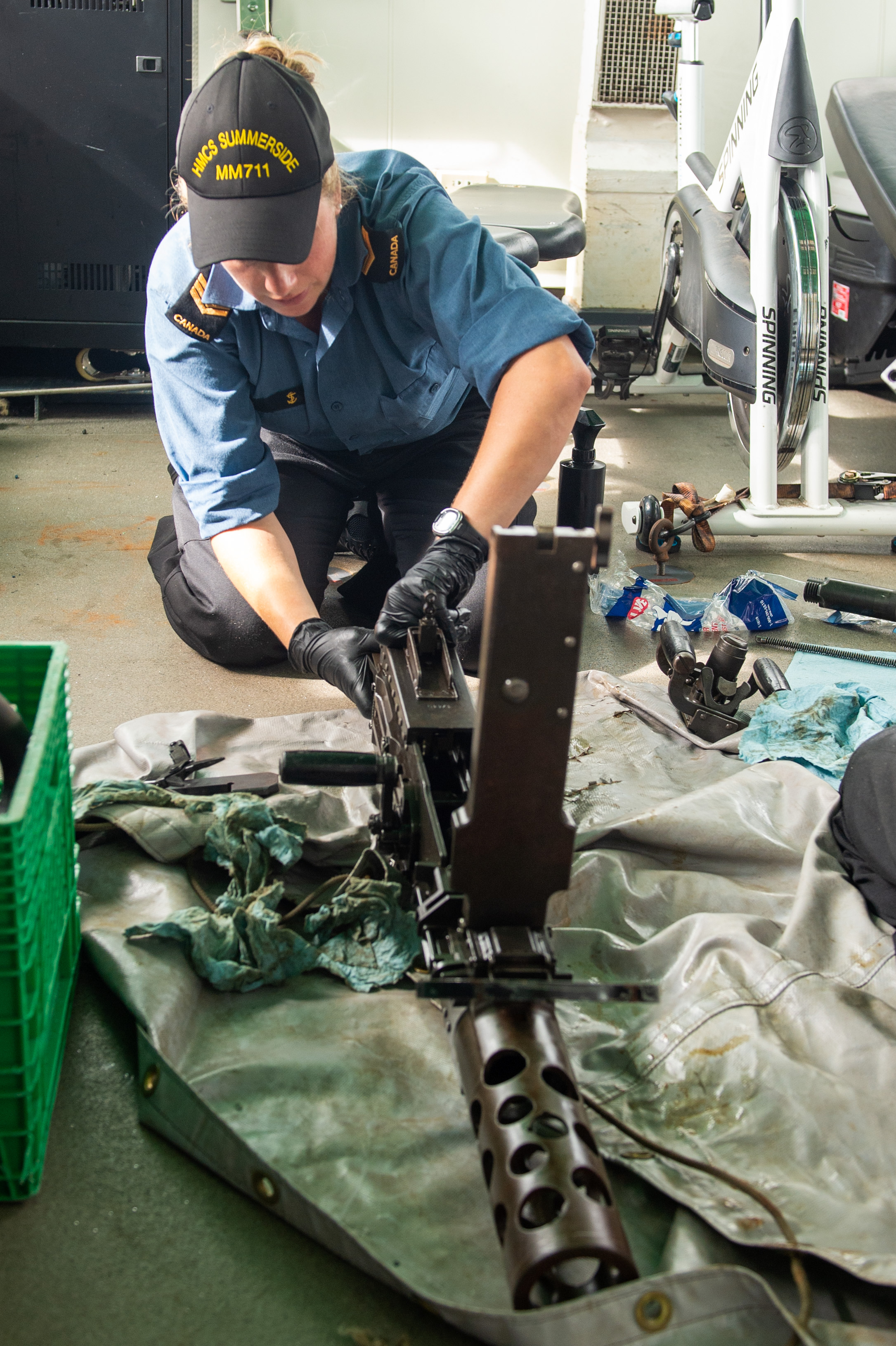 A Royal Canadian Navy member cleans the .50 calibre heavy machine gun onboard HMCS Summerside while sailing in the Atlantic Ocean during Operation CARIBBE on November 2, 2020.