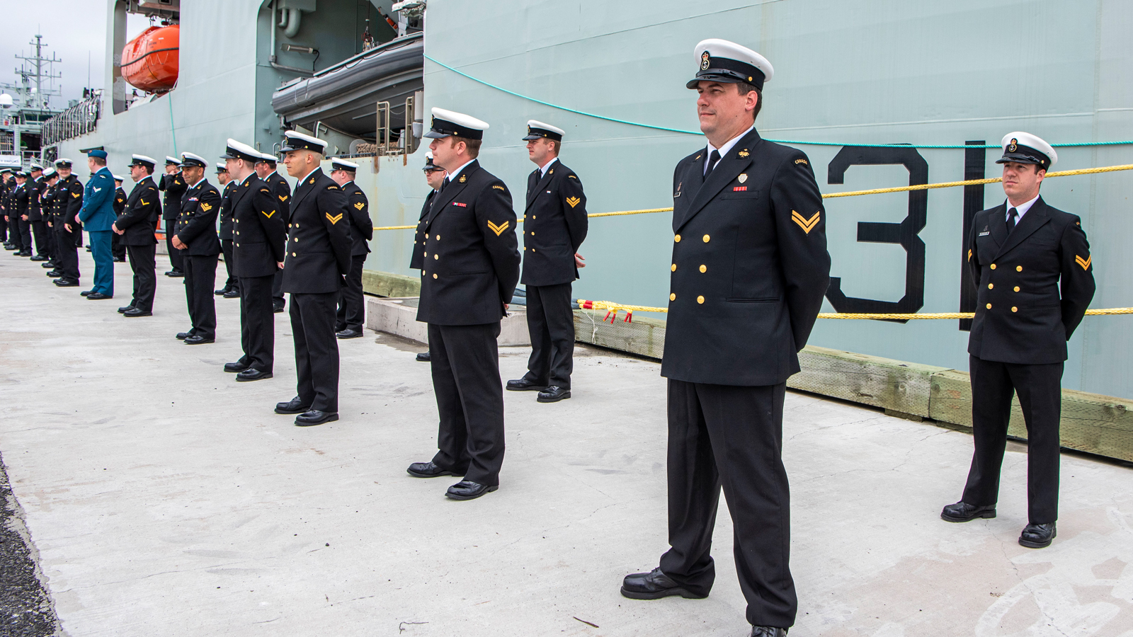 Crew members of the future HMCS Margaret Brooke line the jetty